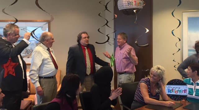 man with pink shirt talking to a group of people